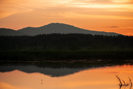 mountains covered with forest, beautiful magical sunset, reflection in water, wallpaper with a beautiful evening landscape, with copy spaceの写真素材