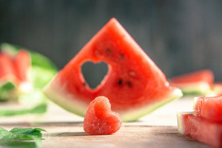 A cut piece of watermelon with a heart-shaped hole. concept Summer, joy, happiness, delicious foodの写真素材