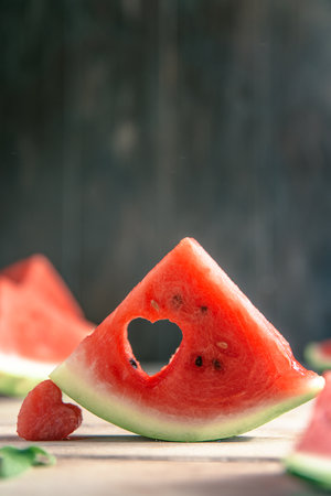 A cut piece of watermelon with a heart-shaped hole. concept Summer, joy, happiness, delicious foodの写真素材