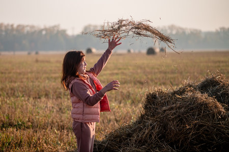 Cute teenage girl in field with wheat clippings and haystacks. morning, fogの写真素材