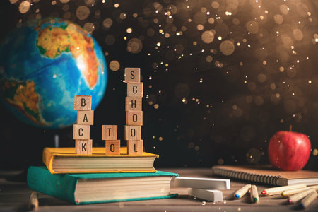 Books, globe, apple and stationery lie on the table against the chalkboardof a black blackboard. Education, September 1, new academic year with copy spaceの写真素材