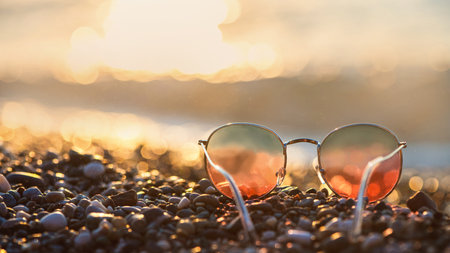 Sunglasses on the background of the sea at sunset, concept summer vacation at the sea with copy spaceの写真素材