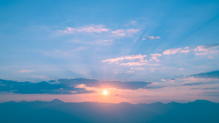 Beautiful clouds at sunset over mountains, rays of sunshine, beautiful light, natural background, calm and tranquilityの写真素材