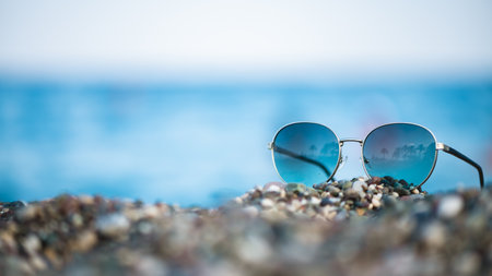 sunglasses on the beach with the sea in the background, palm trees in them, summer vacation