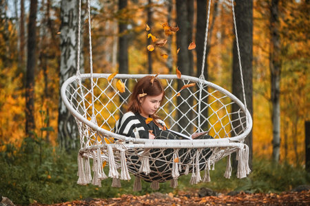 girl with freckles with a book among autumn leaves. reading, magic autumnの写真素材