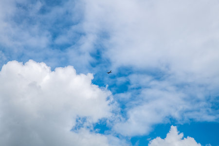 the plane is flying in the sky, beautiful white cumulus clouds in blue sky, natural background, wallpaperの写真素材