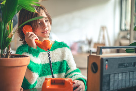 retro, cute girl teen talking on old orange vintage phone with dialerの写真素材