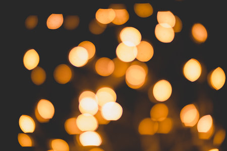 Bright yellow, gold lights, bokeh on black background. festive texture, background for creating fairy lights. overlay, holiday, magic, enchantmentの写真素材
