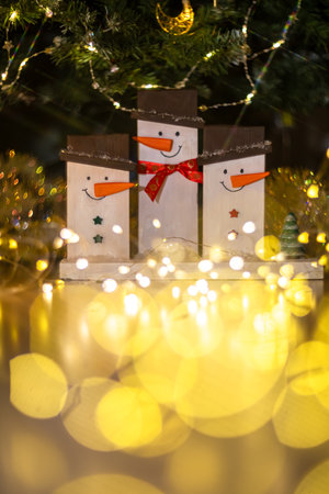 Three homemade snowmen made of boards under the Christmas tree among the garlands. Christmas, New Year, diyの写真素材