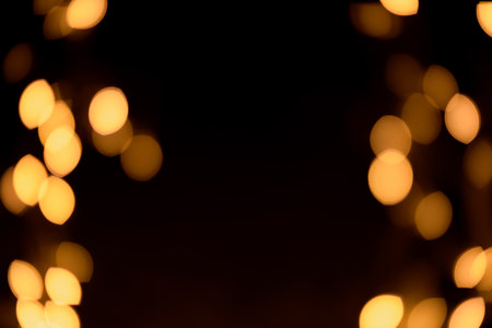 Bright yellow, gold lights, bokeh on black background. festive texture, background for creating fairy lights. overlay, holiday, magic, enchantmentの写真素材