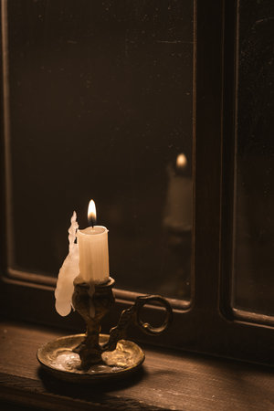 burning candle on windowsill at nightの写真素材