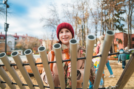Young girl is happily playing music on outdoor tubular bells in an urban parkの写真素材