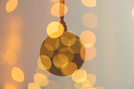 Hanging christmas ball ornament surrounded by a dreamy blur of golden bokeh lights, creating a warm and inviting festive atmosphere, creative multiple exposure effect, christmas backgroundの写真素材