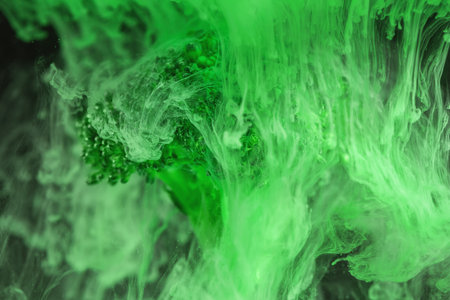 Fresh broccoli with a cloud of green color paint on black background in water. Artistic nutrition...