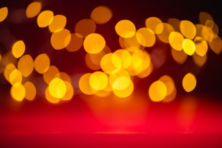 Vibrant golden bokeh lights against a deep red background, creating a warm and inviting ambiance, perfect for festive or cozy settings.の写真素材
