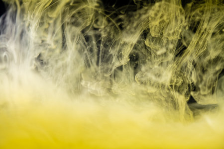 clouds of yellow smoke on a black background, clouds of paint in water, abstract background, textureの写真素材