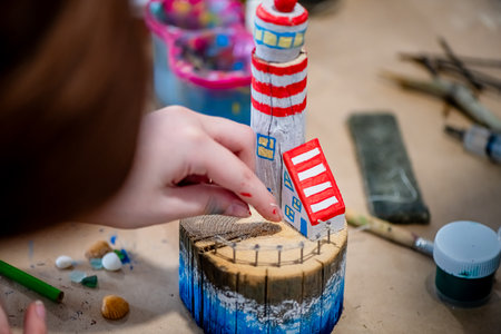 cute teen girl at a master class making a DIY wooden lighthouse made of wood, exhibition of crafts, crafts fair, education, master classes, DIY wood productの写真素材