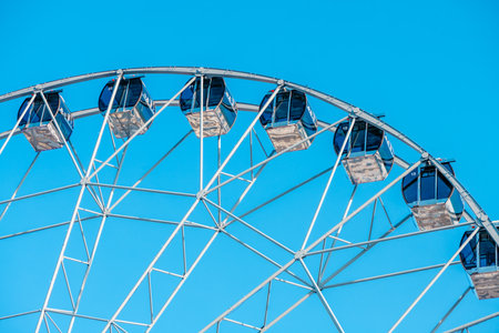 Ferris wheel with empty cabins offers breathtaking views over the amusement park, promising an exciting ride under the vast expanse of a vibrant blue skyの写真素材