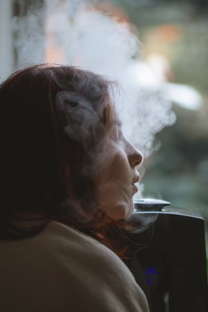 cute teen girl enjoys the benefits of a humidifier, breathing clean and healthy air, improving her respiratory health and overall well-being in the comfort of her homeの写真素材
