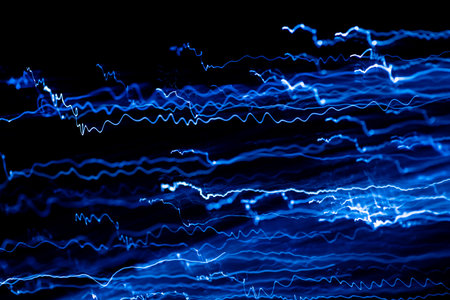 Blue streaks of light are flowing on a black background creating a dynamic and energetic abstract...