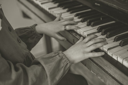 Close up of young girls hands, playing piano. black and white tone effected