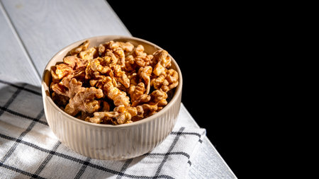Shelled walnuts resting in a bowl on a checkered tablecloth create an inviting scene, complemented...