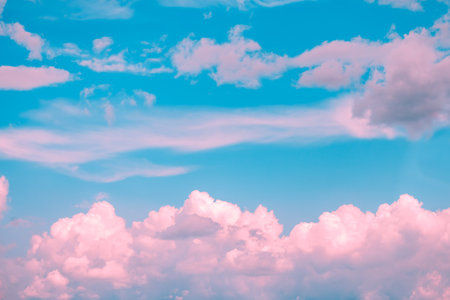 Drifting pink and white cumulus clouds float across a vibrant blue sky, crafting a dreamy and surreal atmosphere that evokes feelings of tranquility and inspirationの写真素材