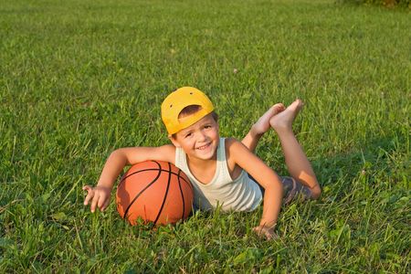 Boy with basketball laying in the grassの写真素材