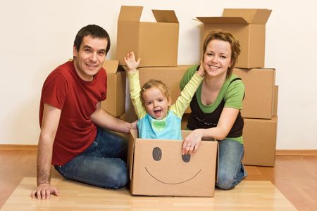 Happy family in their new home sitting on the floor with cardboard boxes aroundの写真素材