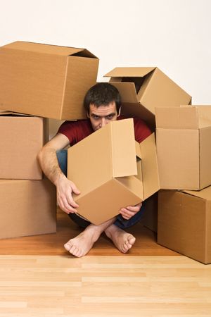 Man under lots of cardboard boxes on the floor - moving concept