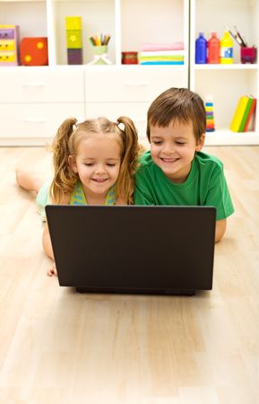 Kids with laptop laying on the floor at homeの写真素材