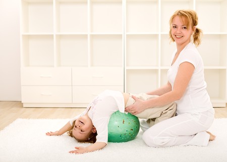 Happy woman and little girl doing gym exercises indoorsの写真素材