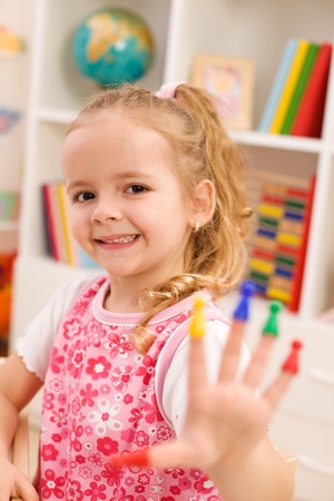 Little girl playing with game pieces fitting them on fingersの写真素材