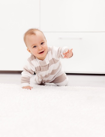 Happy smiling baby girl learns to crawl at homeの写真素材