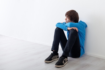 Serious teenager boy thinking and daydreaming while sitting at home Serious teenager boy thinking and daydreaming while sitting at home