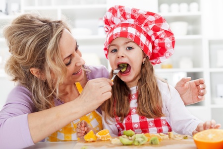 Eating fresh fruits is healthy - woman and little girl in the kitchenの写真素材