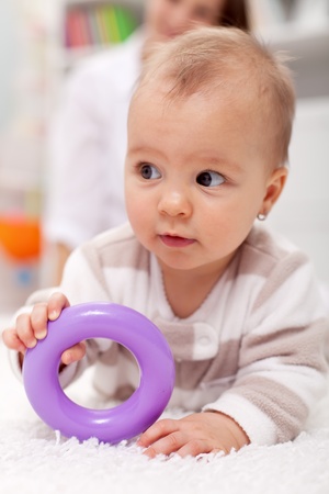 Baby girl on the floor with plastic toyの写真素材