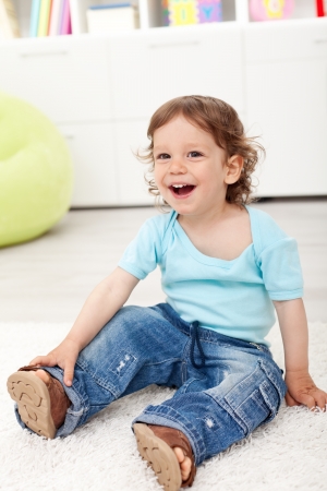 Happy toddler boy sitting on the floor laughingの写真素材