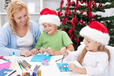 Family around christmas time making greeting cards wearing santa hatsの写真素材