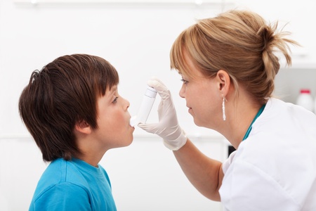 Boy having respiratory illness helped by health professional with inhalerの写真素材
