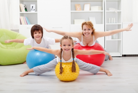 Happy kids exercising with their mother using large rubber ballsの写真素材
