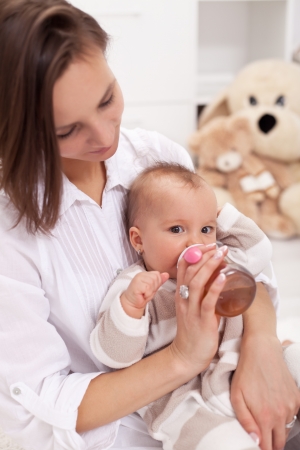 Caring mother feeding baby girl with bottleの写真素材