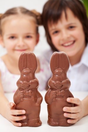 Happy easter kids smiling and holding large chocolate bunnies - closeupの写真素材