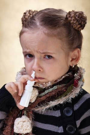 Little girl with the flu using nasal spray reluctantlyの写真素材
