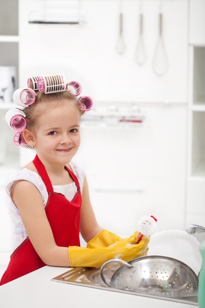 Little girl with big curls doing the dishes - smiling, wearing large glovesの写真素材