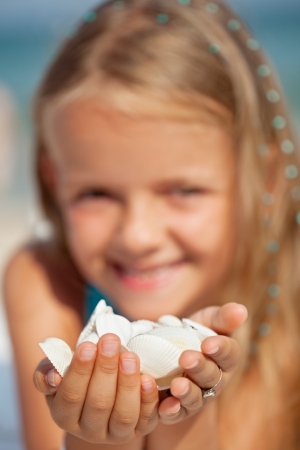 Happy little girl holding seashells - closeup, shallow depthの写真素材