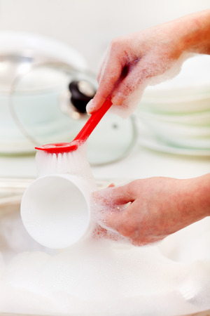 Woman hands washing dishes in the kitchen sink - closeupの写真素材