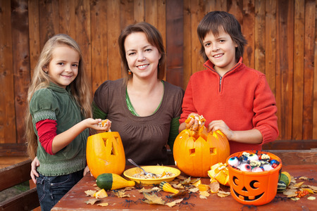 Happy woman and kids preparing for Halloween - carving pumpkin jack-o-lanternsの写真素材