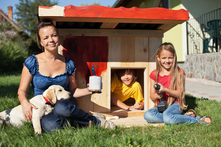 Happy kids painting the doghouse to shelter their new labrador puppyの写真素材