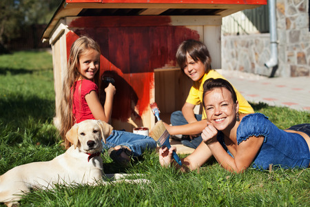 Happy family building a doghouse for their little labrador puppy - paintingの写真素材